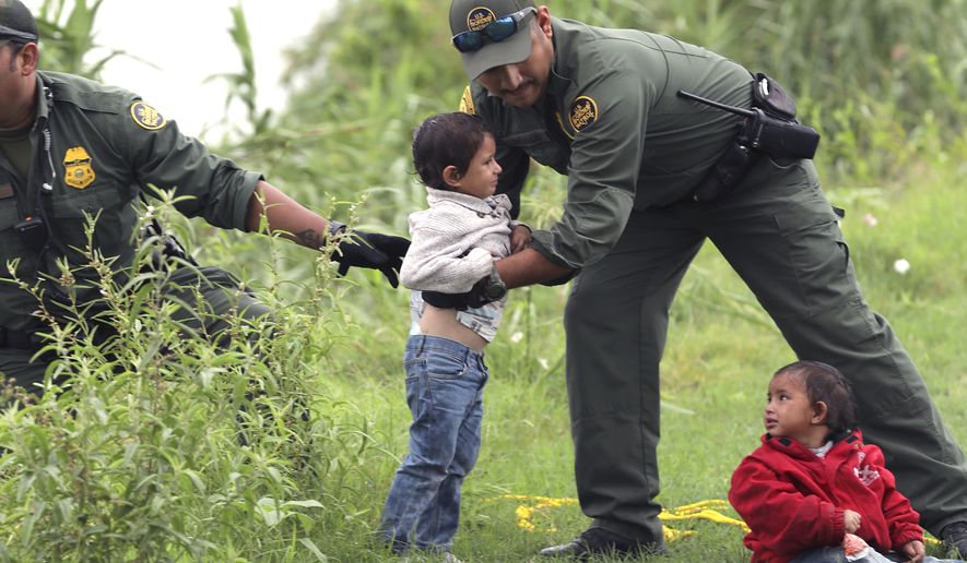 In this Friday, May 10, 2019, file photo, Border Patrol Agents rescue two children from Honduras after their makeshift raft turned over with their mother in it as they were attempting to cross the Rio Grande River near Eagle Pass, Texas. (Bob Owen/The San Antonio Express-News via AP)