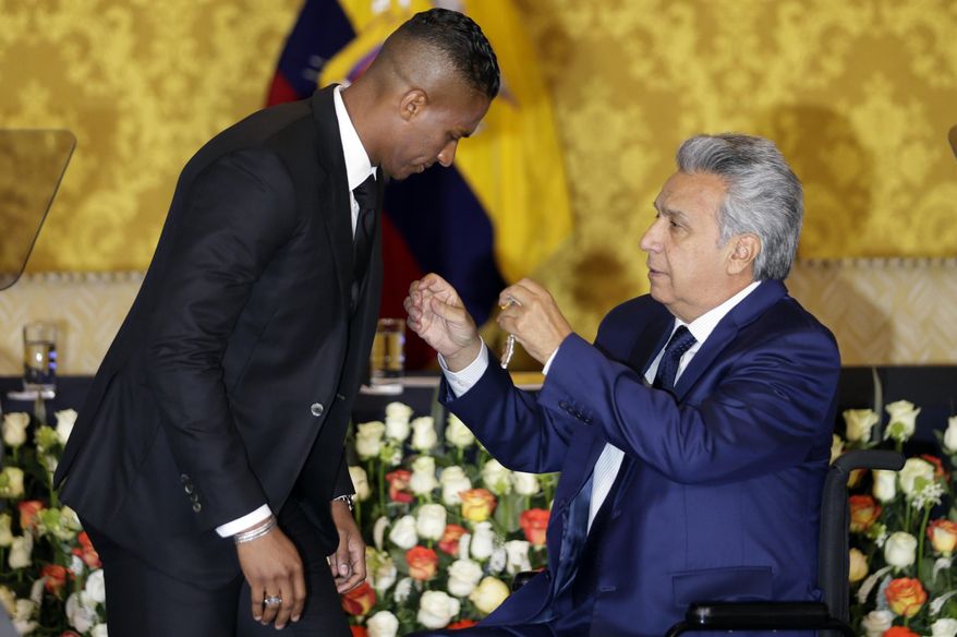 Ecuador's President Lenin Moreno, right, decorates soccer star Antonio Valencia with a National Order of Merit, in Quito, Ecuador, Tuesday, May 14, 2019. The Ecuadorian's final game with Manchester United was Sunday, after 10 seasons with the team. (AP Photo/Dolores Ochoa)