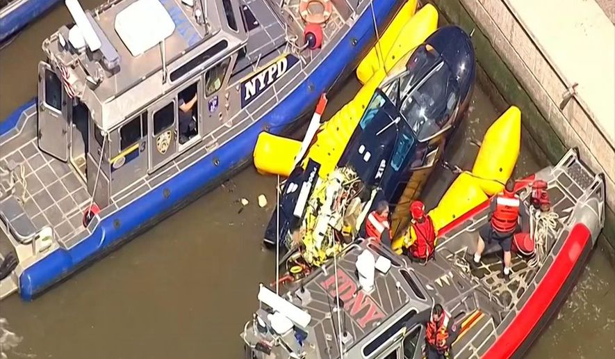 In this image made from video provided by WABC-TV, harbor units from the New York City police and fire departments work to secure a helicopter to the dock after it crashed in the Hudson River, Wednesday, May 15, 2019 in New York. WABC reports that the pilot was ok and that there were no passengers on the aircraft. (WABC-TV via AP)