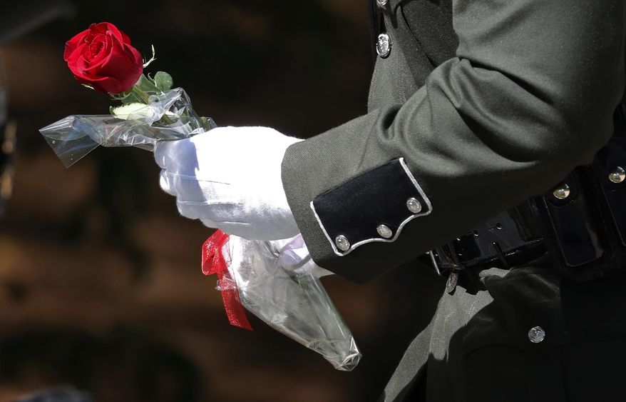 A Mississippi Department of Wildlife, Fisheries and Parks honor guard member prepares to place a rose at the foot of the granite memorial during a memorial service, Wednesday, May 15, 2019, outside headquarters in Jackson, Miss. The service was one of many nationwide during Peace Officers Memorial Day, an observance that pays tribute to the local, state, and federal peace officers who have died, or who have been disabled, in the line of duty. (AP Photo/Rogelio V. Solis)