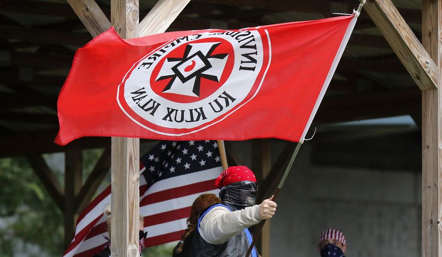 In this Sept. 1, 2018, file photo, a Ku Klux Klan member waves a Klan flag during the Ku Klux Kookout where counterprotests by anti-hate groups were also held at Jaycee Park in Madison, Ind. (Michelle Pemberton/The Indianapolis Star via AP) 