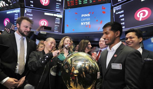 FILE - In this Thursday, April 18, 2019, file photo, Pinterest co-founder and chief product officer Evan Sharp, left, and fellow co-founder &amp;amp; CEO Ben Silbermann, right, watch as company communications manager Enid Hwang rings a ceremonial bell when their IPO begins trading on the New York Stock Exchange floor. Pinterest, fresh off its initial public offering, is reporting a smaller loss in the first quarter, boosted by higher revenue, but its outlook was below expectations and shares slumped in after-hours trading. (AP Photo/Richard Drew, File)