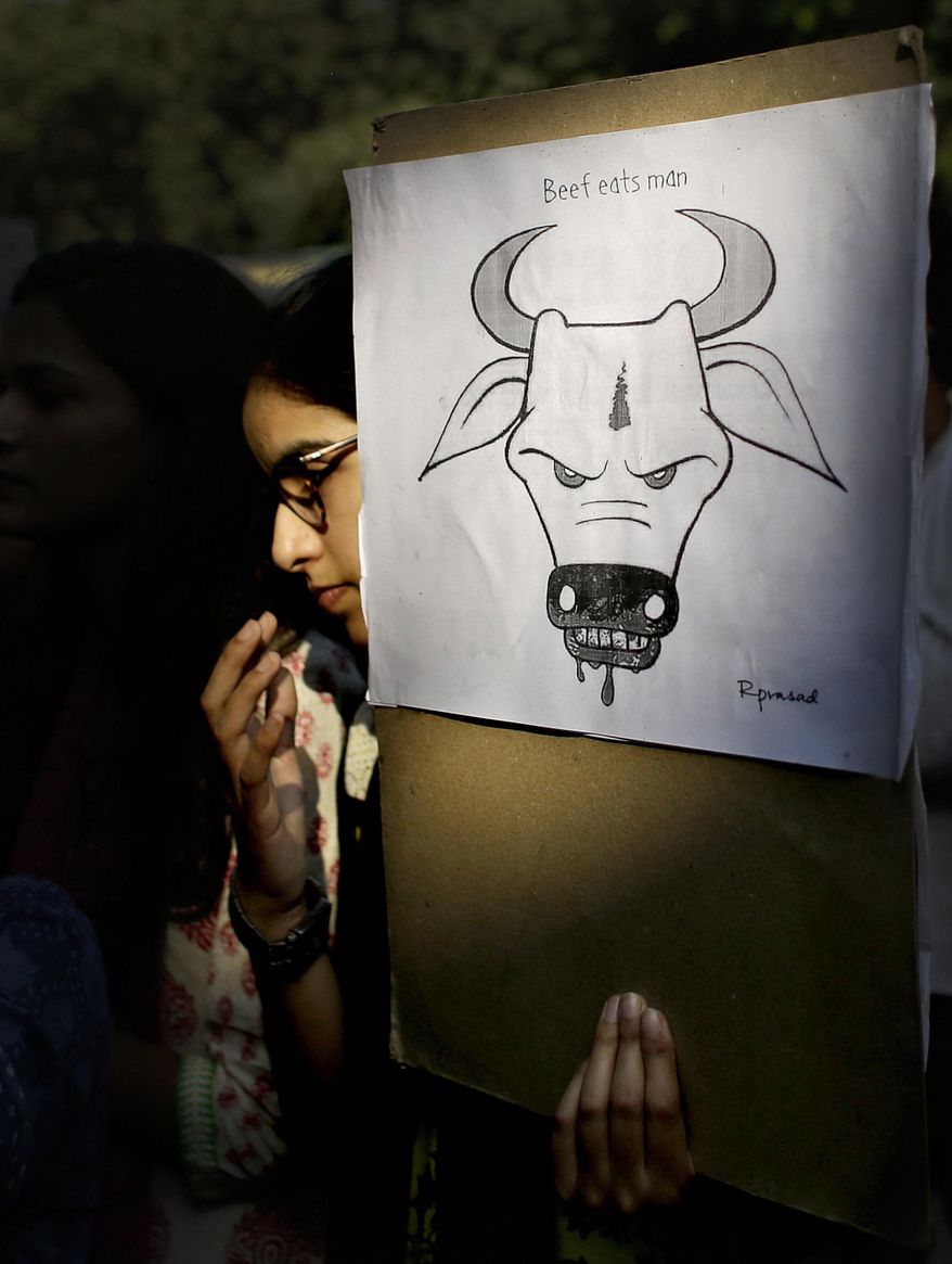 FILE - In this Oct. 2, 2015 file photo, a student activist holds a placard during a protest denouncing the killing of a 52-year-old Muslim farmer Mohammad Akhlaq by villagers upon hearing rumors that the family was eating beef, a taboo for many among India's majority Hindu population, in New Delhi, India. Police and residents say a Muslim man has been shot and killed and another injured by Hindu vigilantes in Indian-controlled Kashmir before dawn Thursday, May 16, 2019, over allegations of smuggling cows. (AP Photo/Altaf Qadri, File)