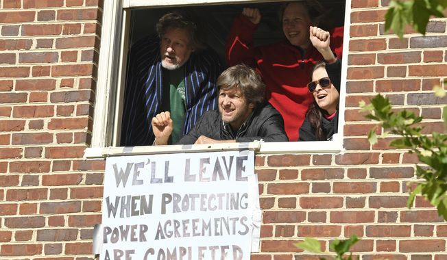 The four activists inside the Venezuelan embassy in Washington look outside the window from a second floor on Tuesday, May 14, 2019. (AP Photo/Susan Walsh)