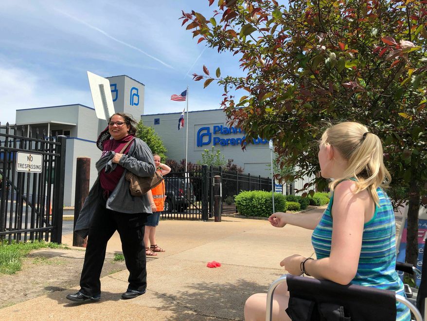 Teresa Pettis, 21, right, greets a passerby outside the Planned Parenthood clinic in St. Louis, Friday, May 17, 2019. Pettis was one of a small number of abortion opponents protesting outside the clinic on the day the Missouri Legislature passed a sweeping measure banning abortions at eight weeks of pregnancy. (AP Photo/Jim Salter) ** FILE **