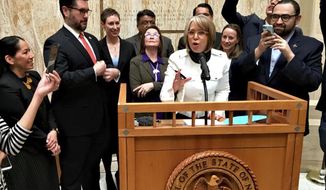 FILE - In this Friday, March 22, 2019 file photo, New Mexico Gov. Michelle Lujan Grisham, surrounded by state lawmakers, cabinet officials and others, signs the Energy Transition Act during a ceremony inside the Roundhouse in Santa Fe, N.M. (Dan McKay/The Albuquerque Journal via AP, File)