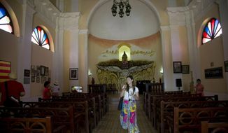 In this May 11, 2019 photo, a tourist walks through a Spanish-style church at the Hermitage of Monserrate, in Matanzas, Cuba. In total, Cuba drew 4.7 million tourists in 2018, a 1.3% rise over the previous year that puts its latest goal of 5 million within reach. (AP Photo/Ismael Francisco)