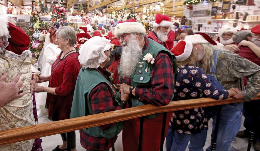 In this Wednesday, May 15, 2019 file photo, Santas and their spouses share hugs and kisses as dozens of Santas visiting Alaska stop by the Santa Claus House in North Pole, Alaska, and renew their wedding vows. (Eric Engman/News-Miner via AP) **FILE**