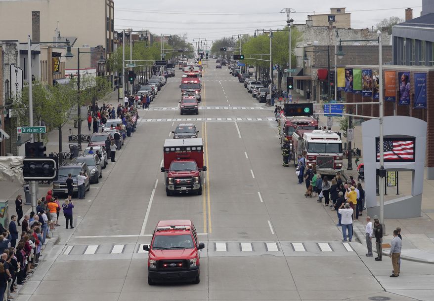 In this Thursday, May 16, 2019 photo, a procession for firefighter Mitch Lundgaard who was shot and killed while responding to a medical call at the Valley Transit Center moves along College Avenue in Appleton, Wis. (Dan Powers/The Post-Crescent via AP)