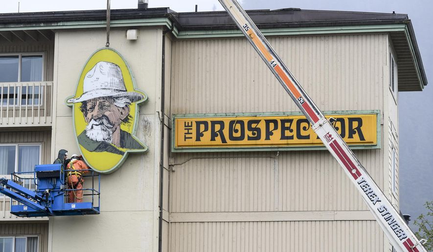 In this Wednesday, May 8, 2019 photo a Juneau Electric crew takes down signage at The Prospector hotel in Juneau, Alaska. As the large, iconic yellow signs came down from the side of the Ramada by Wyndham hotel in Juneau, formerly known as the Prospector Hotel, Jessica Meacham watched with mixed emotions. (Michael Penn/Juneau Empire via AP)