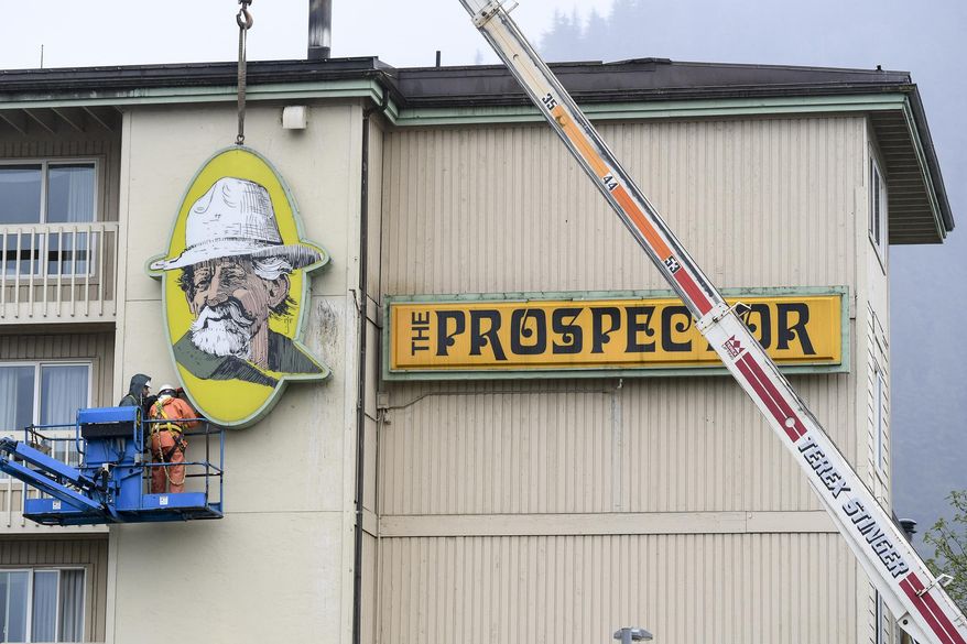 In this Wednesday, May 8, 2019 photo a Juneau Electric crew takes down signage at The Prospector hotel in Juneau, Alaska. As the large, iconic yellow signs came down from the side of the Ramada by Wyndham hotel in Juneau, formerly known as the Prospector Hotel, Jessica Meacham watched with mixed emotions. (Michael Penn/Juneau Empire via AP)