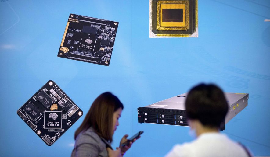 FILE - In this May 18, 2018, file photo, visitors walk past a display showing microchips and circuit boards at the 21st China Beijing International High-tech Expo in Beijing. For four decades, Beijing has cajoled or pressured foreign companies to hand over technology. And its trading partners say if that didn&#x27;t work, China stole what it wanted. (AP Photo/Mark Schiefelbein, File)