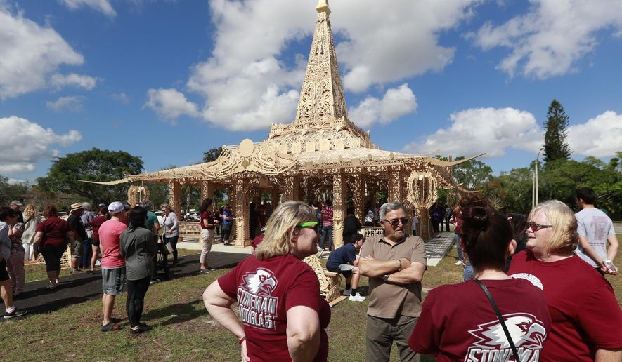 FILE - In this Feb. 14, 2019, file photo, people gather around the "Temple of Time" in honor of the 17 that were killed during the Marjory Stoneman Douglas High School shooting in 2018 in Coral Springs, Fla. The temple built as a memorial to the 17 victims of a Florida high school mass shooting is to be burned to the ground in a symbolic gesture of healing. (AP Photo/Wilfredo Lee, File)