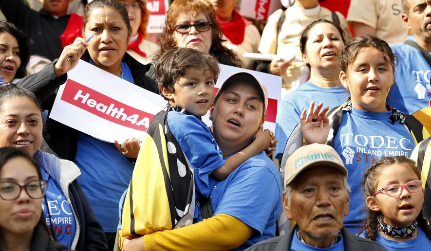 Oralia Sandoval, center, holds her son Benjamin, 6, as she participates in an Immigrants Day of Action rally, Monday, May 20, 2019, in Sacramento, Calif. Gov. Gavin Newsom has proposed offering government-funded health care benefits to immigrant adults ages 19 to 25 who are living in the country illegally. State Sen. Maria Elena Durazo, D-Los Angeles, has proposed a bill to expand that further to include seniors age 65 and older. (AP Photo/Rich Pedroncelli)