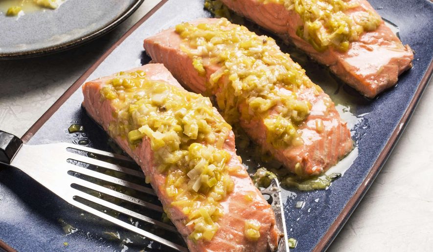 This undated photo provided by America's Test Kitchen in May 2019 shows Salmon with Leeks and White Wine in Brookline, Mass. This recipe appears in the cookbook “How to Braise Everything.” (Carl Tremblay/America's Test Kitchen via AP)