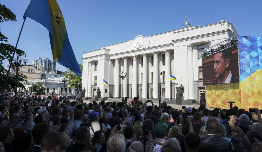 People gather in front of Verkhovna Rada, the Ukrainian parliament, during the inauguration ceremony of new Ukrainian President Volodymyr Zelenskiy, right on the screen, in Kiev, Ukraine, Monday, May 20, 2019. Television star Volodymyr Zelenskiy has been sworn in as Ukraine&#x27;s next president after he beat the incumbent at the polls last month. The ceremony was held at Ukrainian parliament in Kiev on Monday morning. (AP Photo/Evgeniy Maloletka)