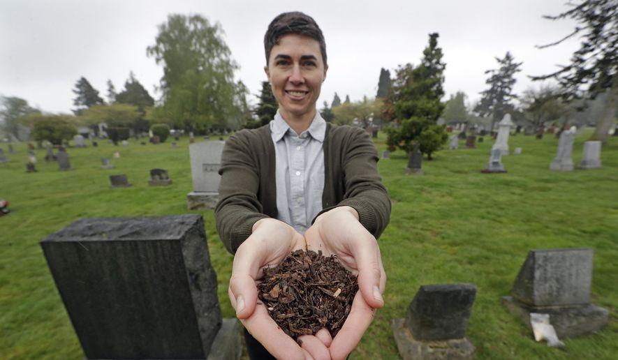 In this April 19, 2019, file photo, Katrina Spade, the founder and CEO of Recompose, a company that hopes to use composting as an alternative to burying or cremating human remains, poses for a photo in a cemetery in Seattle, as she displays a sample of compost material left from the decomposition of a cow using a combination of wood chips, alfalfa and straw. On Tuesday, May 21, 2019, Washington Gov. Jay Inslee signed a bill into law that allows licensed facilities to offer "natural organic reduction," which turns a body, mixed with substances such as wood chips and straw, into soil in a span of several weeks. Th law makes Washington the first state in the U.S. to approve composting as an alternative to burying or cremating human remains. (AP Photo/Elaine Thompson, File) **FILE**