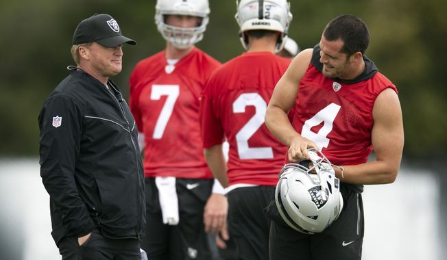 Oakland Raiders head coach Jon Gruen, left, confers with his quarterbacks Mike Glennon (7), Landry Jones (2) and Derek Carr (4) during an NFL football official team activity, Tuesday, May 21, 2019, at team headquarters in Alameda, Calif. (AP Photo/D. Ross Cameron)