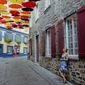 Paule Bergeron takes in the scene in Place-Royale in Old Quebec, Aug. 27, 2018. Quebec City offers compelling urban bike routes along the river, out to Montmorency Falls and through intriguing neighborhoods, as well as access to the Jacques-Cartier rail trail running through forest, farmland and meadows. (AP Photo/Cal Woodward)