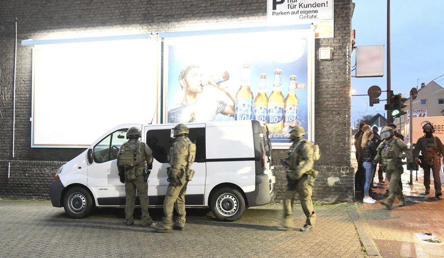 Police officers secure a building in Essen, Germany, Wednesday, May 22, 2019. Police in western Germany are raiding premises linked to an Iraqi gang suspected of involvement in human trafficking, drug dealing, illegal arms trade and forging identity papers. (Stephan Witte/dpa via AP)