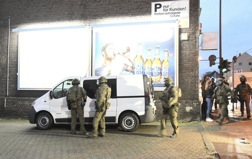 Police officers secure a building in Essen, Germany, Wednesday, May 22, 2019. Police in western Germany are raiding premises linked to an Iraqi gang suspected of involvement in human trafficking, drug dealing, illegal arms trade and forging identity papers. (Stephan Witte/dpa via AP)