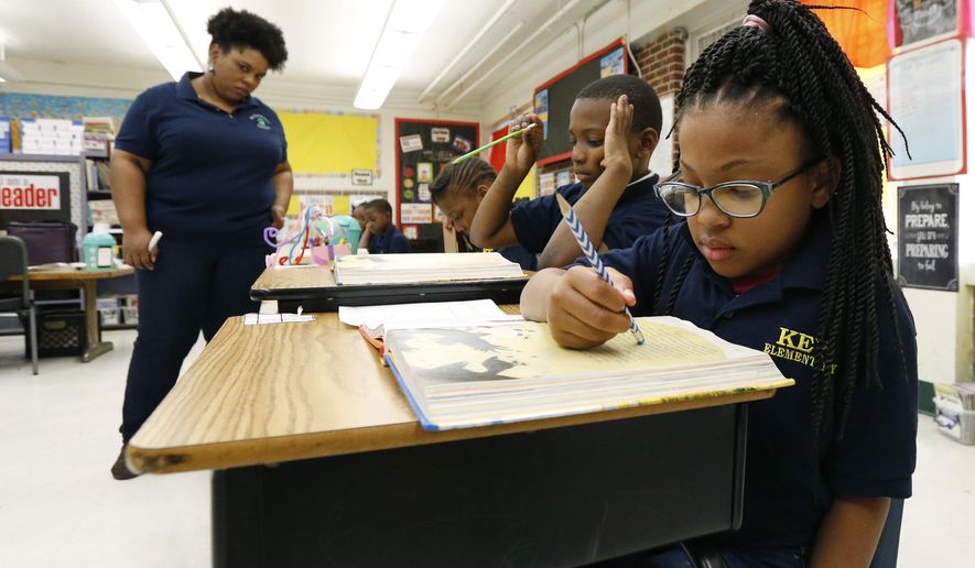 FILE - In this April 18, 2019 file photograph, Elize'a Scott, a Key Elementary School third grade student, right, reads under the watchful eyes of teacher Crystal McKinnis, left, in Jackson, Miss. About one in four Mississippi third graders failed a toughened reading test on the first try this spring, according to results released Wednesday, May 22, 2019, by the Mississippi Department of Education, leaving it unclear if the students will advance to fourth grade. (AP Photo/Rogelio V. Solis, File)