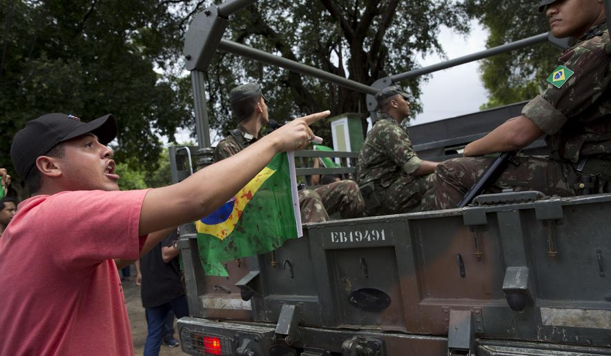 FILE - In this April 10, 2019 file photo, a friend of Evaldo dos Santos Rosa, shot and killed by soldiers, points and shouts at a soldier during a protest outside an army's barrack in Rio de Janeiro, Brazil. A top Brazilian military court has ordered on Thursday, May 23, nine soldiers to be released while they await trial in the April shooting that killed two people in Rio de Janeiro, an incident that caused national outrage. (AP Photo/Silvia Izquierdo, File)
