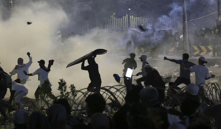 Supporters of the losing presidential candidate throw rocks towards police Wednesday, May 22, 2019, in Jakarta, Indonesia. Indonesian President Joko Widodo said authorities have the volatile situation in the country's capital under control after a number of people died Wednesday in riots by supporters of his losing rival in last month's presidential election. (AP Photo/Achmad Ibrahim)