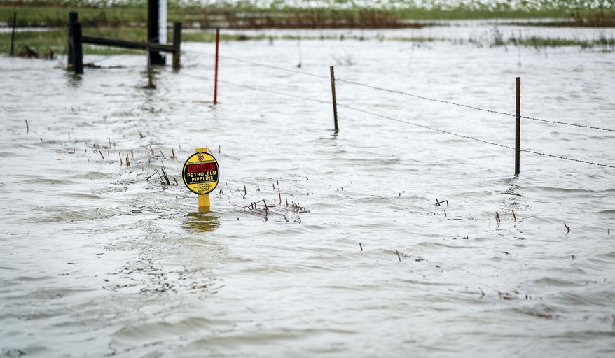 Water has collected along the road side and almost covered up a gas pipeline sign in Rapid City, S.D. on Wednesday, May 22, 2019. (Adam Fondren/Black Hills Pioneer via AP)