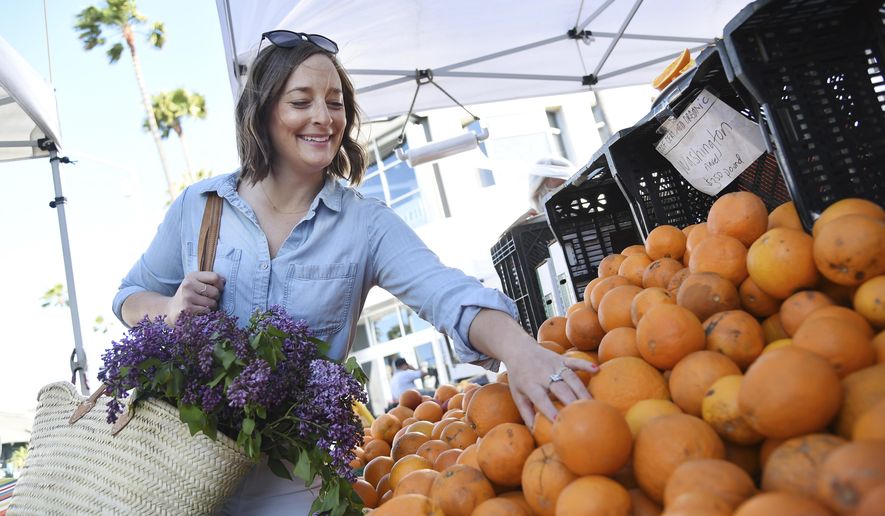 This April 10, 2019 photo shows Gaby Dalkin shopping for oranges at Santa Monica Downtown Farmers Market in Santa Monica, Calif. Dalkin, the chef behind the popular Website and social media accounts, "What’s Gaby Cooking," is forging her own path. Every Monday she posts a live demo to Instagram as she cooks dinner which has become appointment viewing for some fans. Her husband films it and reads questions from viewers as she’s cooking. (AP Photo/Chris Pizzello)