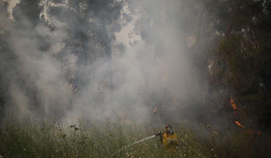 Fire fighters extinguish a forests fire near Kfar Uriya, Thursday, May 23, 2019. Israeli police have ordered the evacuation of several communities in southern and central Israel as wildfires rage amid a major heatwave. (AP Photo/Ariel Schalit)