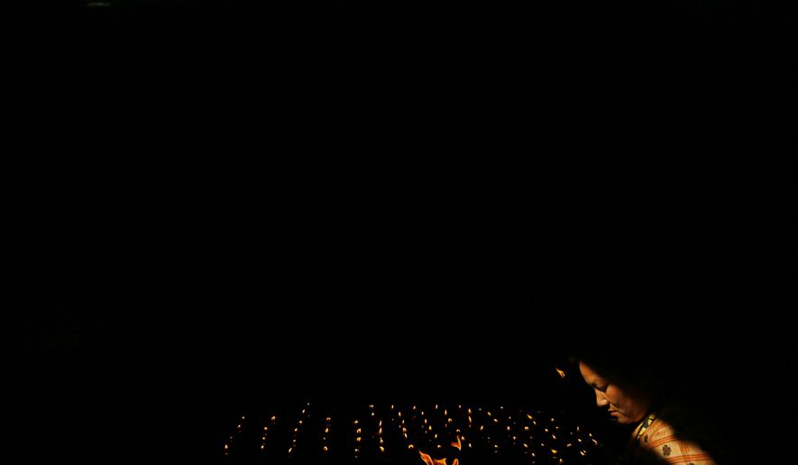 In this Saturday, May 18, 2019, file photo, a Nepalese Buddhist woman lights a butter lamp during Buddha Jayanti, or Buddha Purnima, festival in Kathmandu, Nepal. The festival marks the triple events of Gautam Buddha's life: his birth, his enlightenment and his attaining a state of Nirvana that frees believers from the circle of death and rebirth. (AP Photo/Niranjan Shrestha, File)
