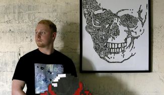 In this May 17, 2019 photo, artist Tanner Rhines poses in his studio in Fairbanks, Alaska. Rhines is an Alaska artist, but is by no means an Alaskana artist. He takes inspiration from modern artists such as abstract expressionists Mark Rothko and Jeff Koons, the artist famous for his stainless steel balloon animals. Many of Rhines&#39; drawings are tiny cartoon details contained in a simple silhouette of an image such as a skull or a Pokemon character. He calls this approach &amp;quot;condention,&amp;quot; a word he made up when he was in high school. It&#39;s based on the word &amp;quot;compression,&amp;quot; and Rhines defines it as a &amp;quot;psychological labyrinth of characters and life energies.&amp;quot; (Eric Engman/Fairbanks Daily News-Miner via AP)