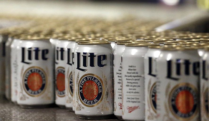 FILE - In this March 11, 2015 file photo, newly-filled and sealed cans of Miller Lite beer move along on a conveyor belt, at the MillerCoors Brewery, in Golden, Colo. A Wisconsin judge on Friday, May 24, 2019, ordered Anheuser-Busch to stop suggesting in advertising that MillerCoors&#39; light beers contain corn syrup, wading into a fight between two beer giants that are losing market share to small independent brewers. (AP Photo/Brennan Linsley, File)