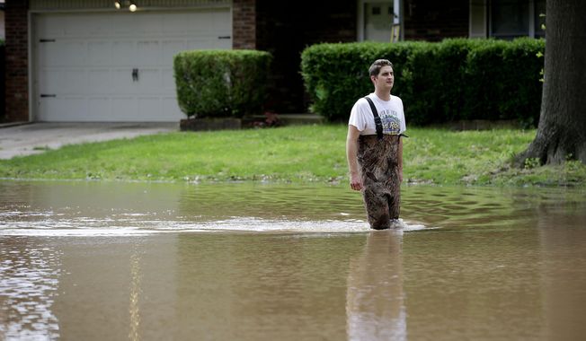 Grant Scepanski walks through his Indian Springs Estates neighborhood in Broken Arrow, Okla., as flood water from the Arkansas River rises Friday, May 24, 2019. (Mike Simons/Tulsa World via AP)