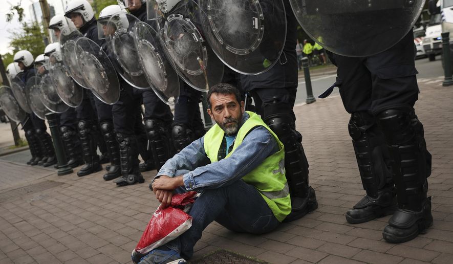 A yellow vest protestor sits in front of a line of police during a demonstration in Brussels, Sunday, May 26, 2019. The demonstration took place as Belgium took to the polls to elect regional, national and European candidates. (AP Photo/Francisco Seco)