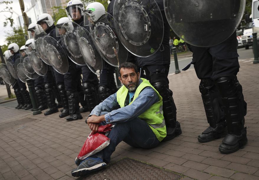A yellow vest protestor sits in front of a line of police during a demonstration in Brussels, Sunday, May 26, 2019. The demonstration took place as Belgium took to the polls to elect regional, national and European candidates. (AP Photo/Francisco Seco)