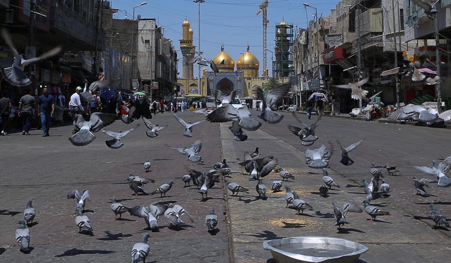 In this Wednesday, May 21, 2019, photo, pigeons fly outside the golden-domed shrine of Imam Moussa al-Kadhim in Kadhimiya district in north Baghdad, Iraq. Many shop owners in the Shiite holy neighborhood of Kadhimiya, have seen their sales drop sharply over the past year since U.S. President Donald began reimposing sanctions on Iran, home to the largest number of Shiite Muslims around the world. (AP Photo/Khalid Mohammed)