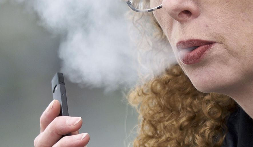 In this April 16, 2019, photo, a woman exhales while vaping from a Juul pen e-cigarette in Vancouver, Wash. (AP Photo/Craig Mitchelldyer) **FILE**