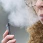 In this April 16, 2019, photo, a woman exhales while vaping from a Juul pen e-cigarette in Vancouver, Wash. (AP Photo/Craig Mitchelldyer) **FILE**