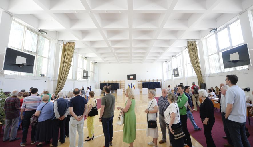 People wait in line to cast their vote as a higher than usual voter turnout is registered shortly after noon at 19.75 percent in Bucharest, Romania, Sunday, May 26, 2019. Romanians vote in the European Parliament elections and a referendum called by Iohannis on judicial system laws.(AP Photo/Andreea Alexandru)