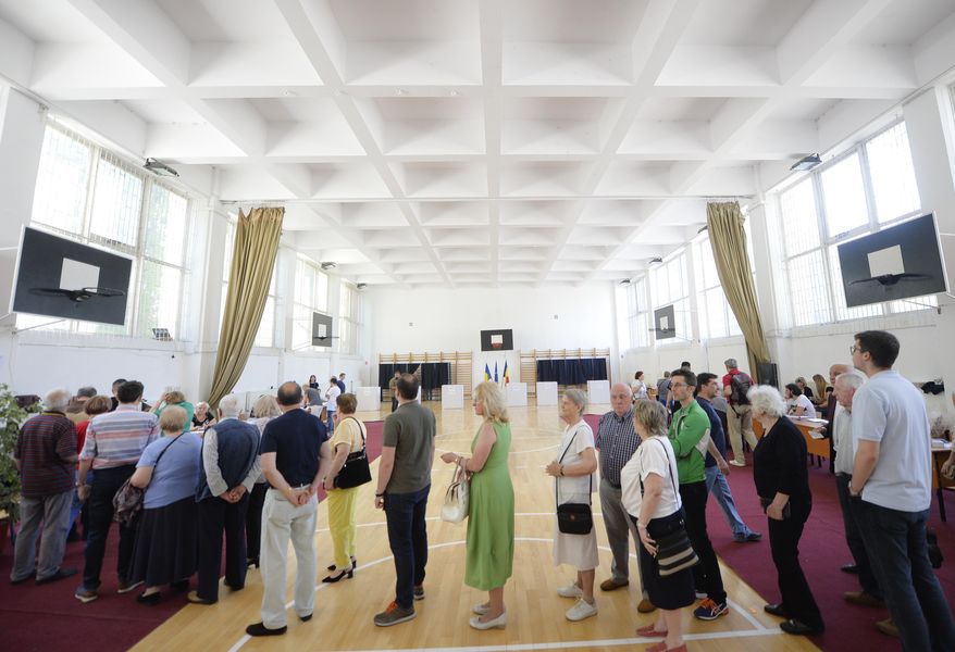 People wait in line to cast their vote as a higher than usual voter turnout is registered shortly after noon at 19.75 percent in Bucharest, Romania, Sunday, May 26, 2019. Romanians vote in the European Parliament elections and a referendum called by Iohannis on judicial system laws.(AP Photo/Andreea Alexandru)