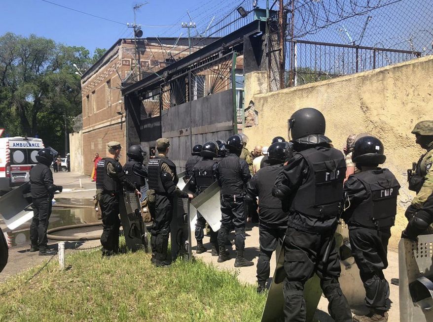 In this photo made available by Ukraine's Police Press Service, riot police stand at the prison in Odessa, Ukraine Monday, May 27, 2019. Police says four prison guards have been injured in clashes with inmates who have barricaded themselves in a prison in Ukraine's port city of Odessa. Serhiy Shaykhet, chief of the investigative unit at the Odessa police, said in televised remarks Monday that police are negotiating with the inmates. (Ukrainian Police Press Office via AP)