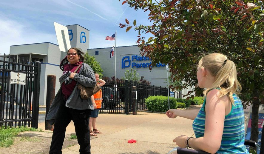 FILE - In this May 17, 2019 file photo, Teresa Pettis, right, greets a passerby outside the Planned Parenthood clinic in St. Louis. Pettis was one of a small number of abortion opponents protesting outside the clinic on the day the Missouri Legislature passed a sweeping measure banning abortions at eight weeks of pregnancy. Planned Parenthood says Missouri&#39;s only abortion clinic could be closed by the end of the week because the state is threatening to not renew its license, which expires Friday, May 31. (AP Photo/Jim Salter, File)