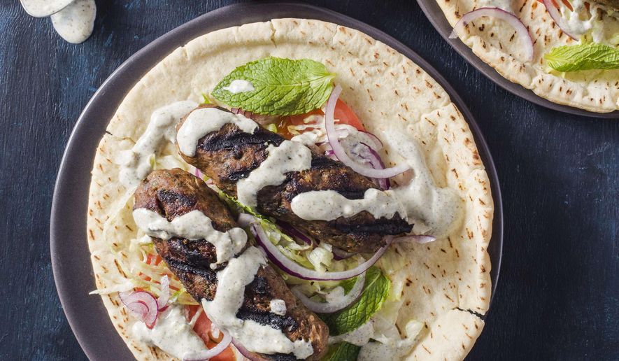 This undated photo provided by America's Test Kitchen in May 2019 shows Grilled Lamb Kofte with Yogurt Sauce in Brookline, Mass. This recipe appears in the cookbook “Spiced.” (Carl Tremblay/America's Test Kitchen via AP)
