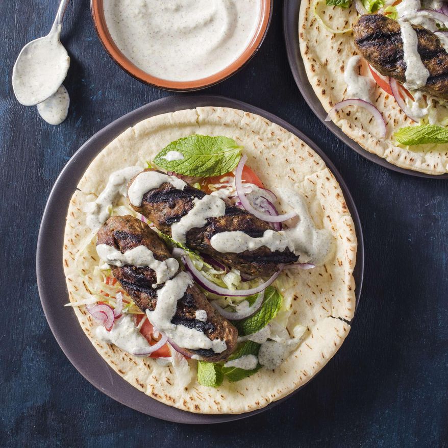 This undated photo provided by America's Test Kitchen in May 2019 shows Grilled Lamb Kofte with Yogurt Sauce in Brookline, Mass. This recipe appears in the cookbook “Spiced.” (Carl Tremblay/America's Test Kitchen via AP)