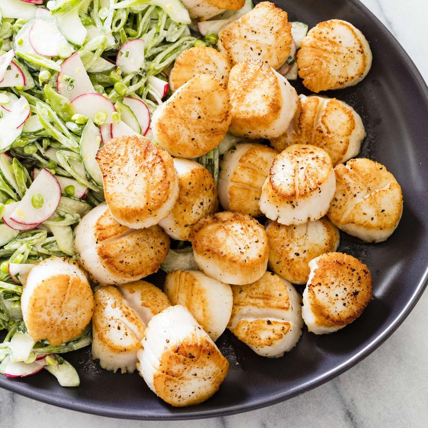 This undated photo provided by America's Test Kitchen in May 2019 shows Pan-Seared Scallops with Slaw in Brookline, Mass. This recipe appears in the cookbook “Vegetables Illustrated.” (Daniel J. van Ackere/America's Test Kitchen via AP)