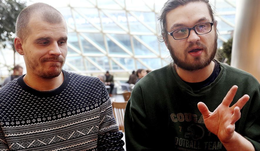 In this Friday, Jan. 19, 2018 photo two Belrusian men, Adam Bialiatski, left and Mikita Valadzko, right, speak to The Associated Press in Warsaw, Poland. A Polish court has sentenced the two to prison for organizing a 2017 stunt in which they and other young adults stripped naked at Auschwitz and chained themselves together to the 'Arbeit Macht Frei' gate as one man slaughtered a sheep. They insist the act was an artistic performance protesting wars in Syria and Ukraine. The Polish court found that they desecrated the Holocaust remembrance site.(AP Photo/Czarek Sokolowski, file)