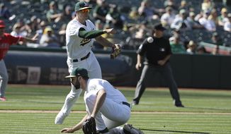 Oakland Athletics&#39; Matt Olson, top, makes a throwing error that scored Los Angeles Angels&#39; Cesar Puello during the eleventh inning of a baseball game in Oakland, Calif., Wednesday, May 29, 2019. (AP Photo/Jeff Chiu)