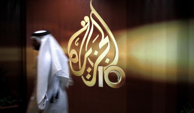 In this Nov. 1, 2006, photo, a Qatari employee of Al-Jazeera Arabic language TV news channel walks past the logo of Al-Jazeera in Doha, Qatar. (AP Photo/Kamran Jebreili) **FILE**